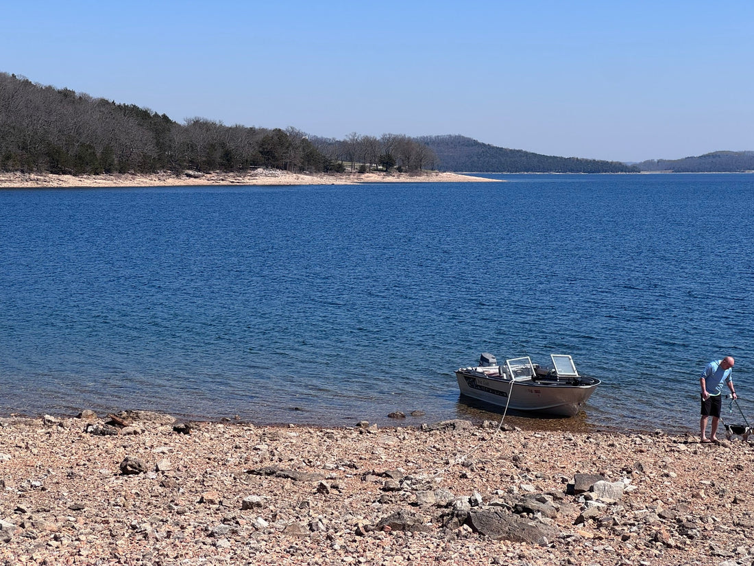 Small aluminum boat fishing rocky shoreline on Beaver Lake Arkansas for smallmouth bass